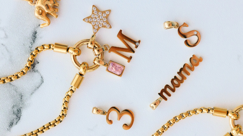 Gold jewelry with various charms on a marble surface