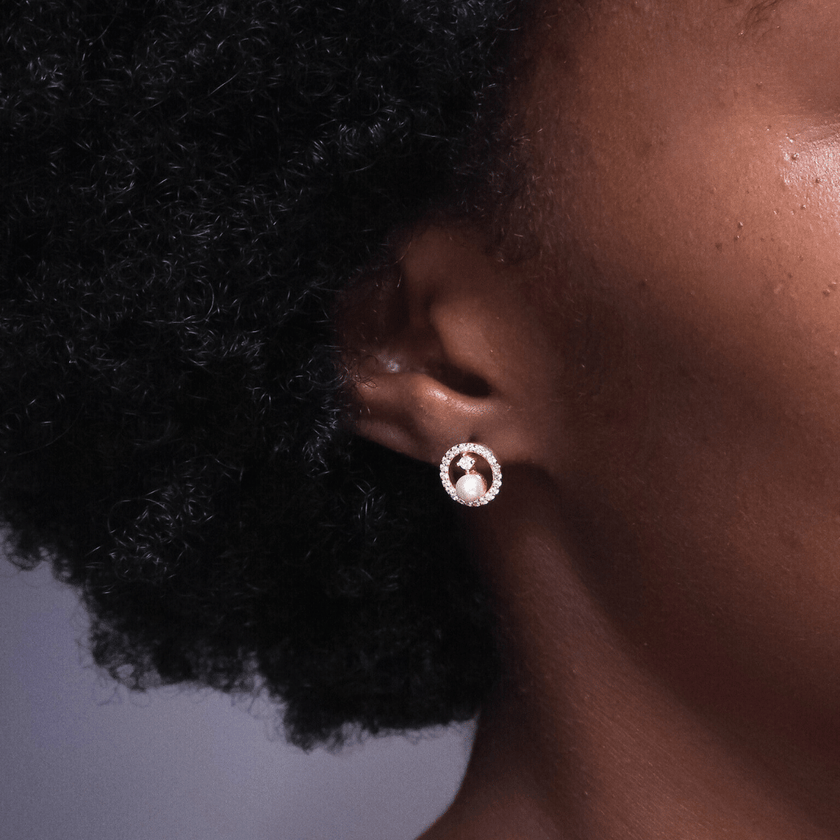 girl wearing small sparkling 14 karat gold earrings featuring crystal halos around real freshwater pearls 