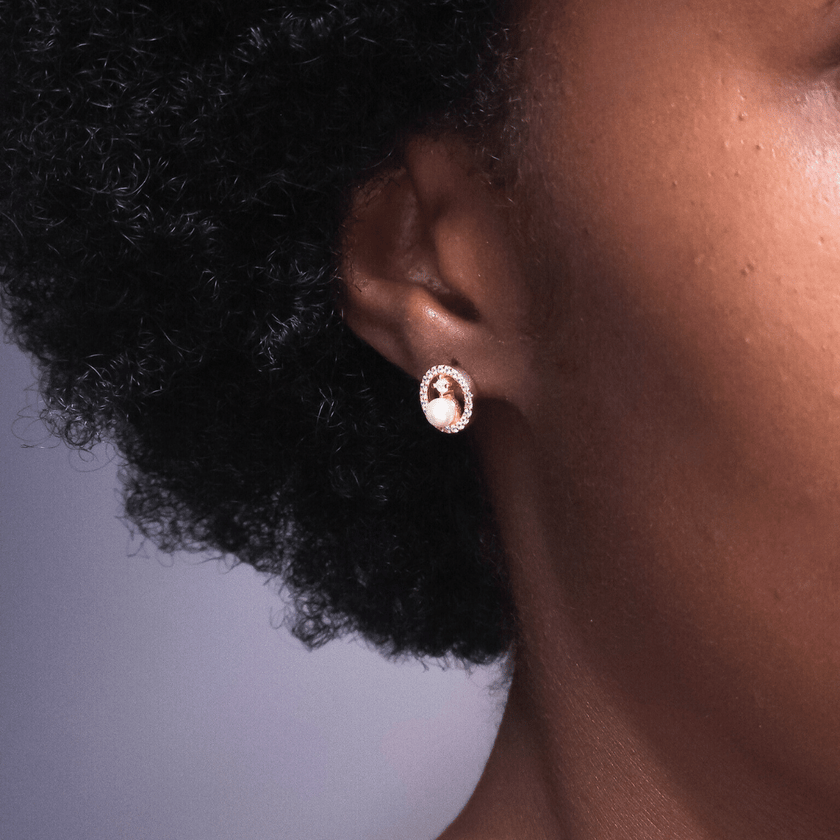 closeup of 14 karat gold plated sterling silver earrings featuring sparkling crystal halos around white freshwater pearls