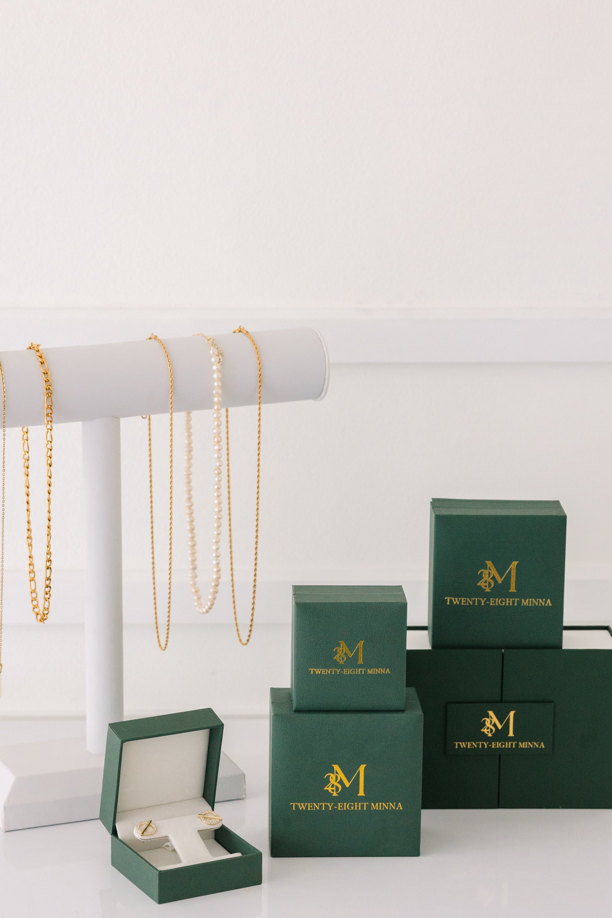 Green jewelry boxes with gold jewelry on a white background
