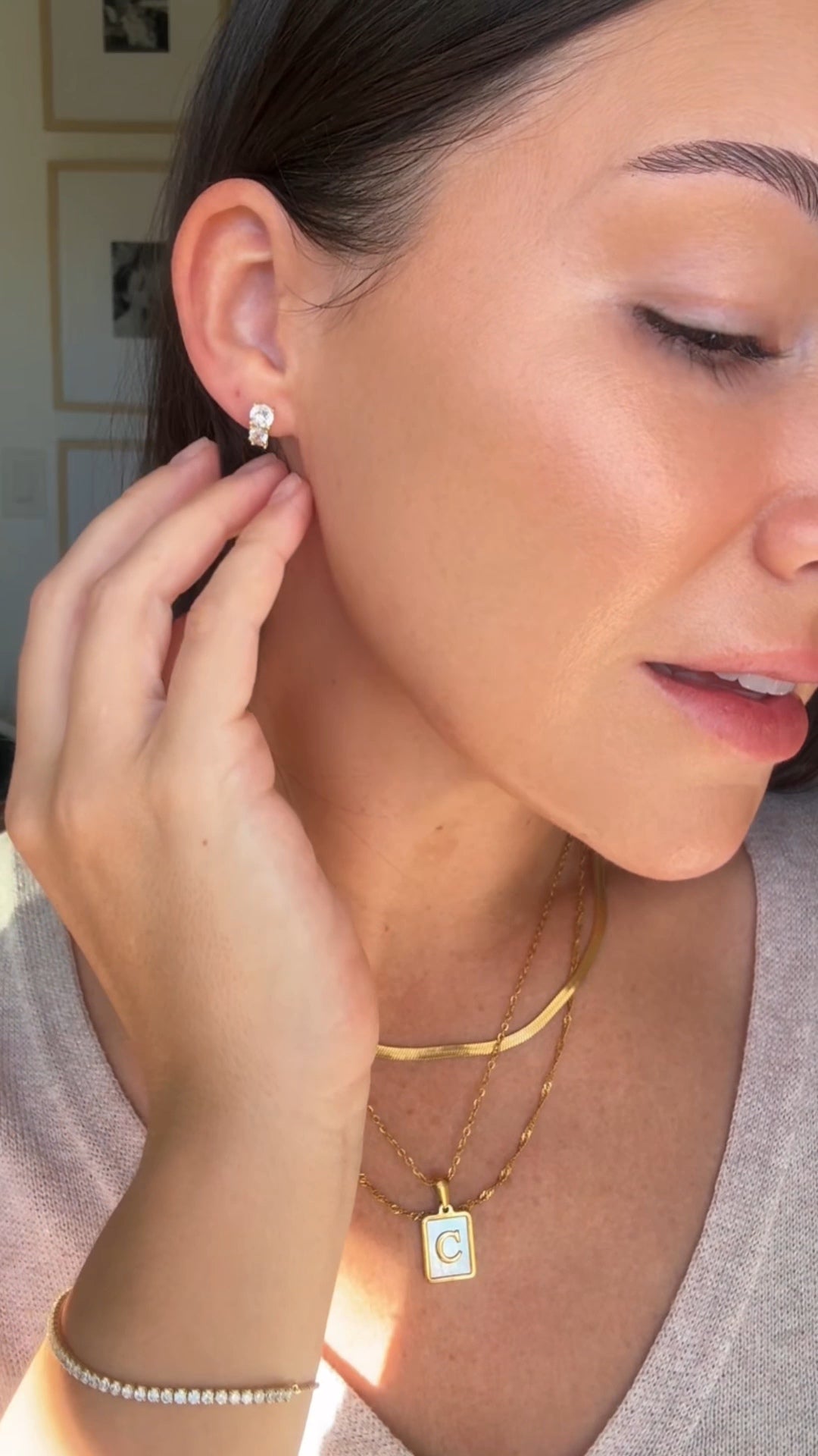 Woman wearing gold earrings and necklaces, with a close-up of an earring.