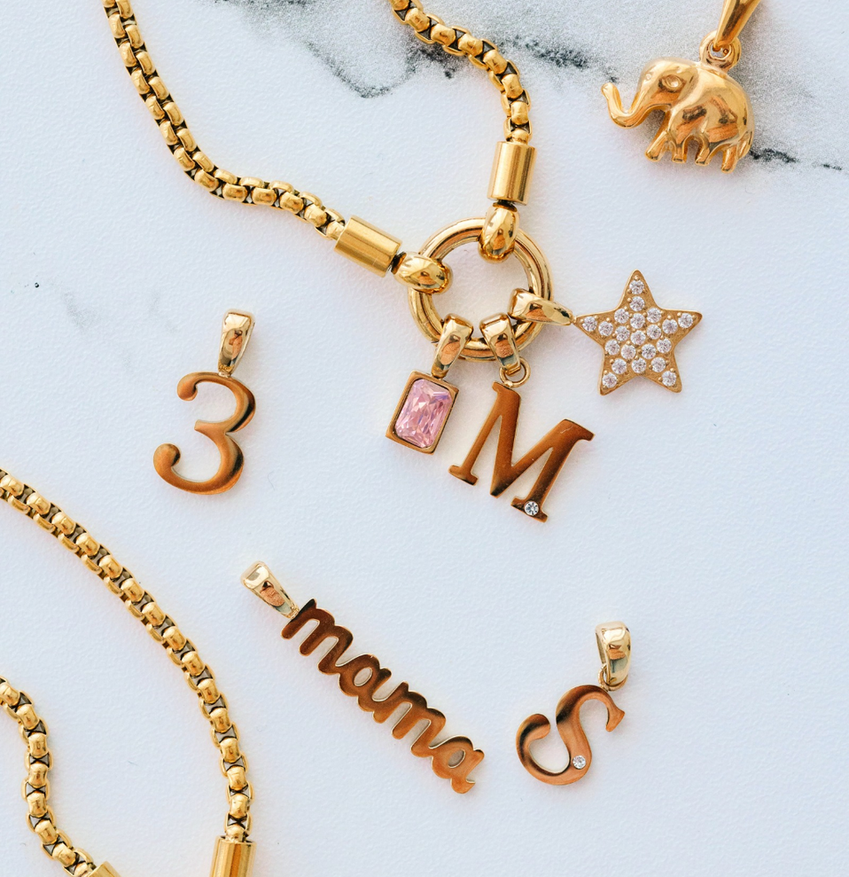 Gold jewelry with various charms on a marble surface