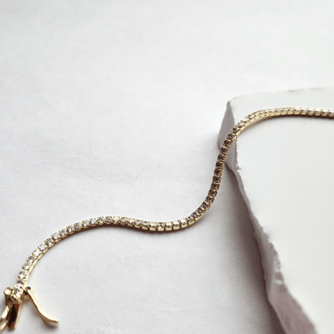 Gold bracelet with clear stones on a bright white surface