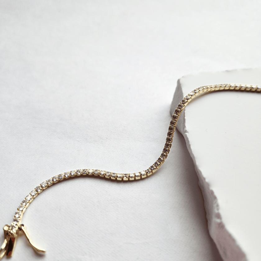 Gold bracelet with clear stones on a bright white surface