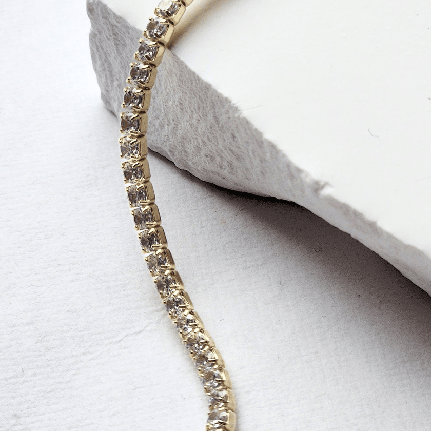 Gold bracelet with diamonds on a white stone surface
