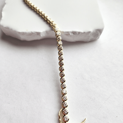 Gold bracelet with small diamonds on a white stone surface