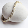 Gold bracelet with clear stones on a white stone surface