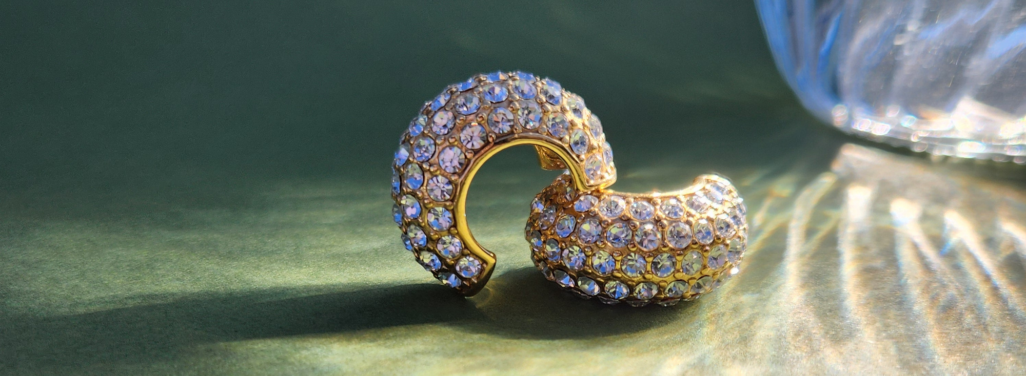 Gold earring with gemstones on a green surface
